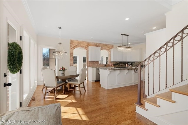 dining space with a notable chandelier, light wood finished floors, recessed lighting, stairway, and ornamental molding