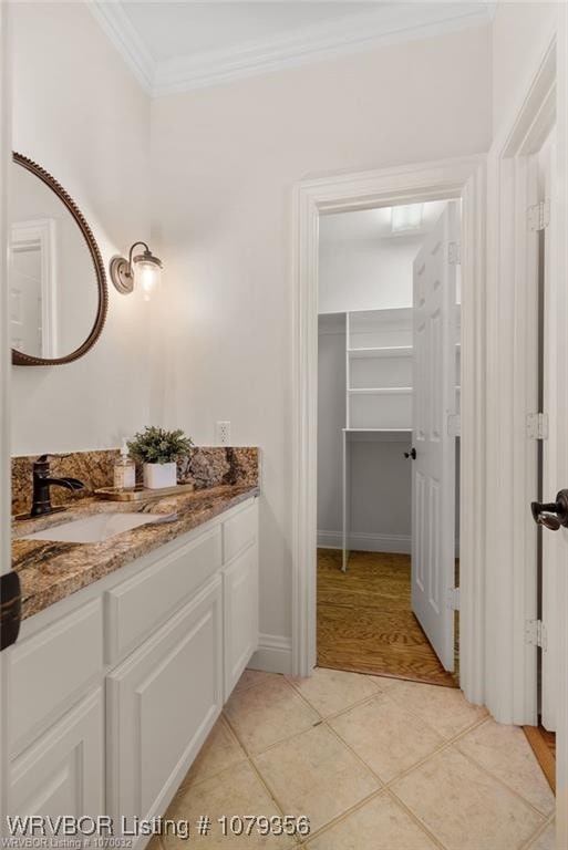 bathroom with vanity, baseboards, crown molding, and tile patterned floors