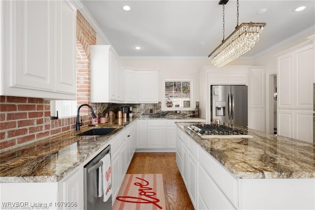 kitchen with stainless steel appliances, a sink, ornamental molding, decorative backsplash, and light wood finished floors