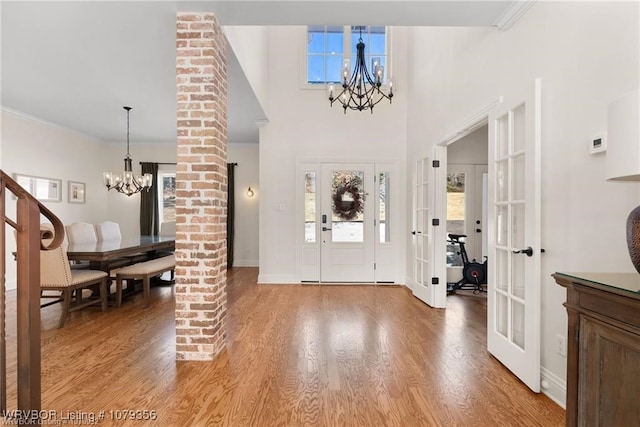 foyer entrance with light wood-style floors, crown molding, and an inviting chandelier