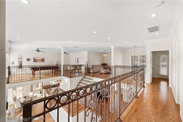 hallway with recessed lighting, crown molding, visible vents, light wood-type flooring, and ornate columns