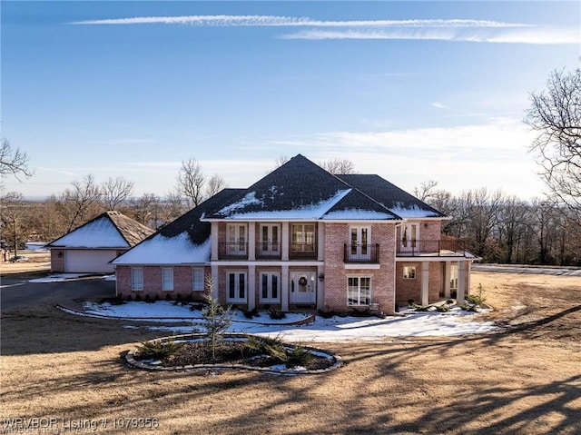 view of front of house with brick siding, french doors, a balcony, and a garage