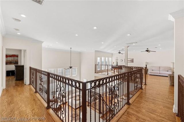 corridor with recessed lighting, visible vents, light wood-style flooring, ornamental molding, and an upstairs landing