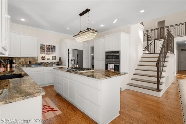 kitchen with light wood-style flooring, appliances with stainless steel finishes, a sink, and a center island