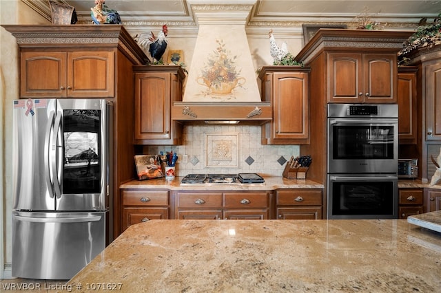 kitchen featuring light stone countertops, backsplash, crown molding, custom range hood, and appliances with stainless steel finishes