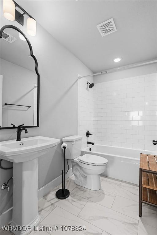 full bathroom featuring sink, tiled shower / bath combo, and toilet