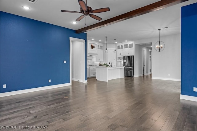 unfurnished living room with dark hardwood / wood-style flooring, sink, ceiling fan with notable chandelier, and beam ceiling