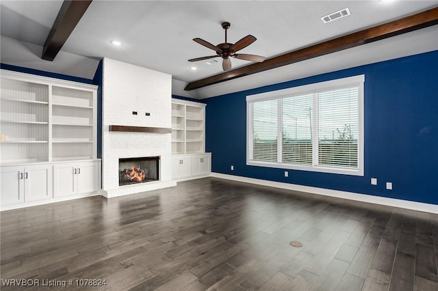 unfurnished living room featuring beam ceiling, a fireplace, dark hardwood / wood-style floors, and ceiling fan