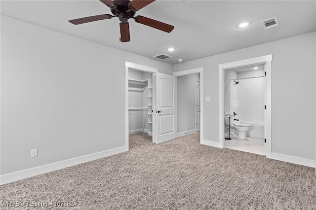 unfurnished bedroom featuring ensuite bathroom, a walk in closet, ceiling fan, light carpet, and a closet