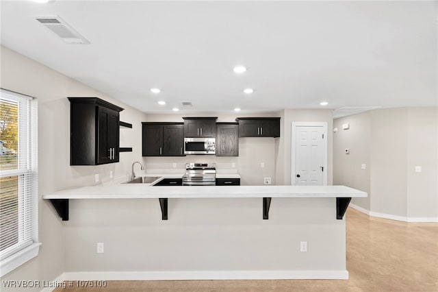 kitchen featuring a kitchen breakfast bar, kitchen peninsula, sink, and appliances with stainless steel finishes