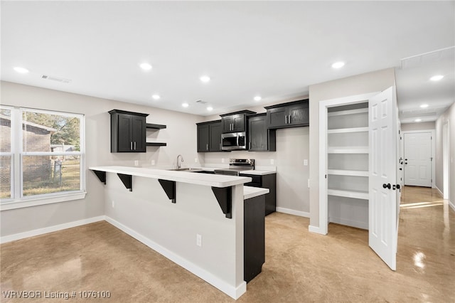 kitchen with sink, kitchen peninsula, stainless steel appliances, and a breakfast bar area