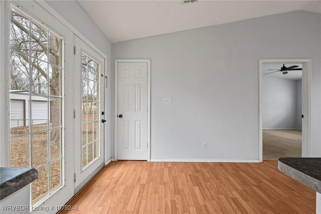 entryway with lofted ceiling, light wood-style flooring, and baseboards