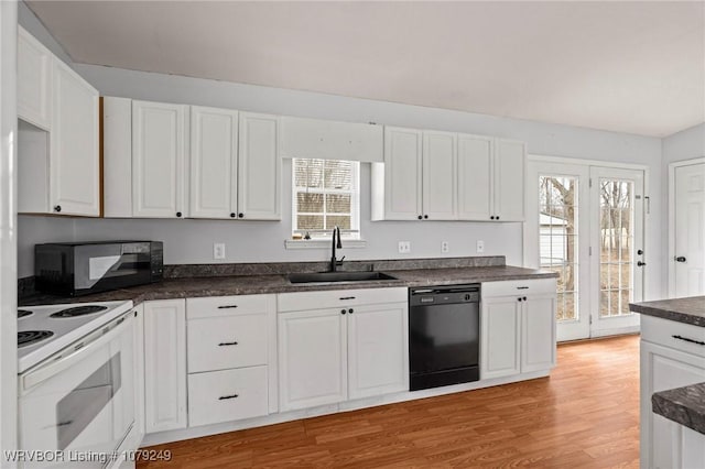 kitchen with dark countertops, white cabinetry, a sink, light wood-type flooring, and black appliances