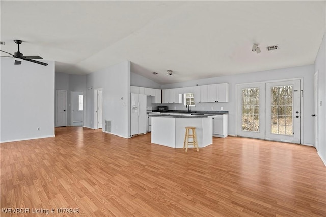 kitchen featuring visible vents, dark countertops, open floor plan, light wood-style floors, and white cabinetry