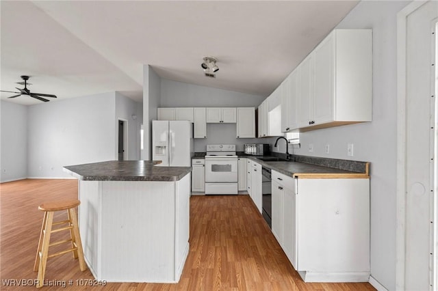 kitchen featuring white appliances, white cabinets, dark countertops, a kitchen island, and light wood-type flooring