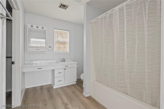 bathroom featuring visible vents, toilet, shower / tub combo, vanity, and wood finished floors