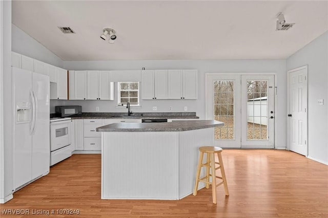 kitchen with white appliances, visible vents, light wood-style flooring, and white cabinetry