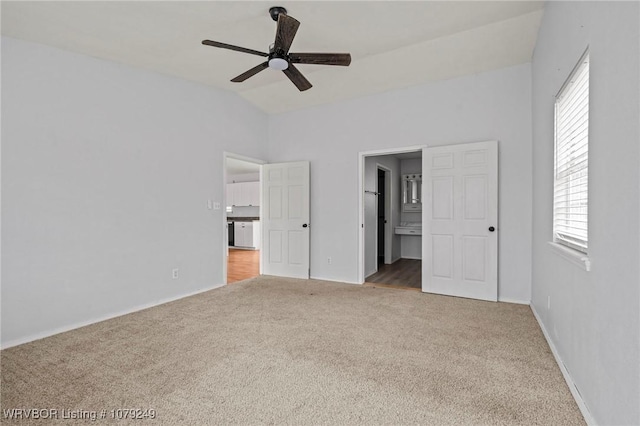 unfurnished bedroom featuring carpet, baseboards, vaulted ceiling, and connected bathroom