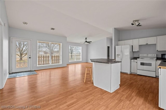 kitchen featuring dark countertops, white appliances, light wood-style flooring, and white cabinets