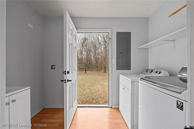 clothes washing area featuring light wood-type flooring, laundry area, electric panel, and washer and dryer