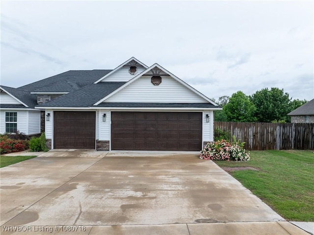 view of front facade featuring an attached garage, fence, a front lawn, driveway, and roof with shingles