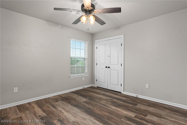 unfurnished bedroom featuring baseboards, a closet, ceiling fan, and dark wood-type flooring