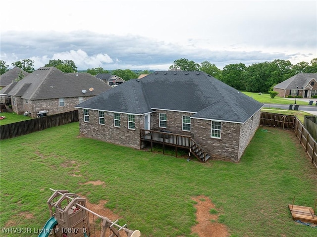rear view of house with a lawn, a deck, and a fenced backyard