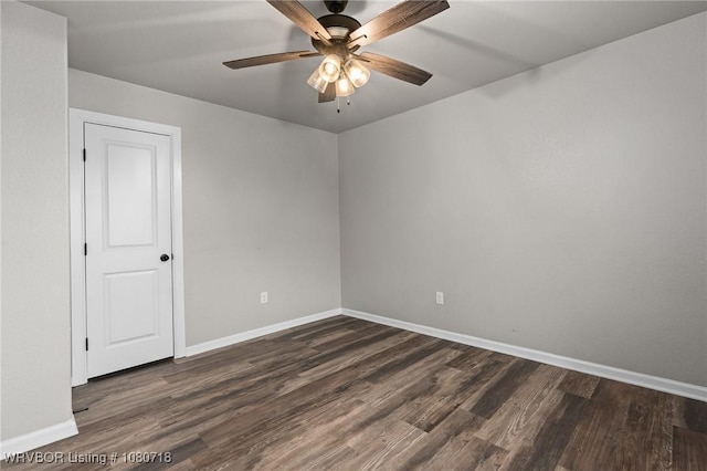 unfurnished room featuring baseboards, a ceiling fan, and dark wood finished floors