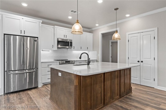 kitchen featuring a sink, stainless steel appliances, wood finished floors, crown molding, and decorative backsplash