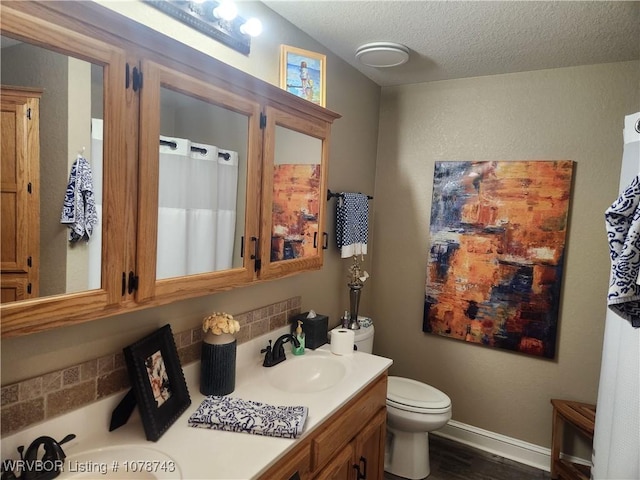 bathroom with hardwood / wood-style floors, tasteful backsplash, vanity, toilet, and a textured ceiling