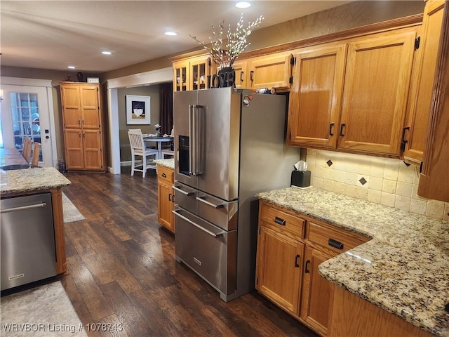 kitchen with light stone counters, stainless steel appliances, dark hardwood / wood-style floors, and tasteful backsplash