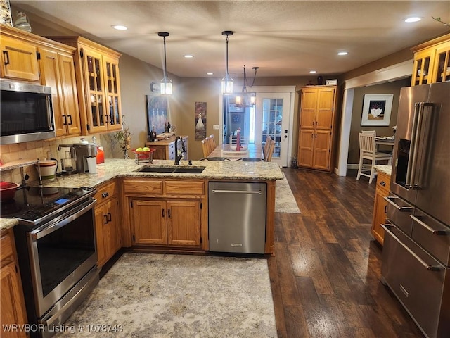 kitchen featuring dark wood-type flooring, sink, decorative light fixtures, kitchen peninsula, and stainless steel appliances