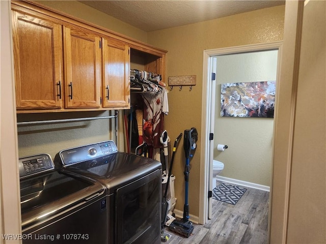 washroom with cabinets, light hardwood / wood-style flooring, independent washer and dryer, and a textured ceiling