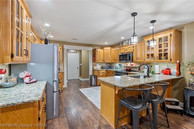 kitchen with sink, appliances with stainless steel finishes, hanging light fixtures, a kitchen bar, and kitchen peninsula