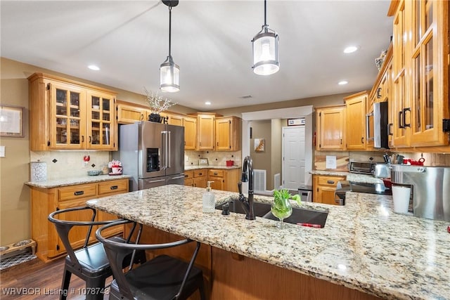 kitchen featuring sink, appliances with stainless steel finishes, hanging light fixtures, light stone counters, and kitchen peninsula