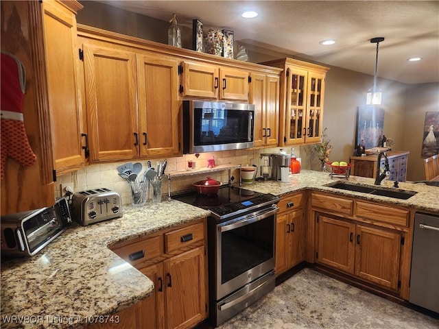 kitchen featuring tasteful backsplash, sink, hanging light fixtures, kitchen peninsula, and stainless steel appliances