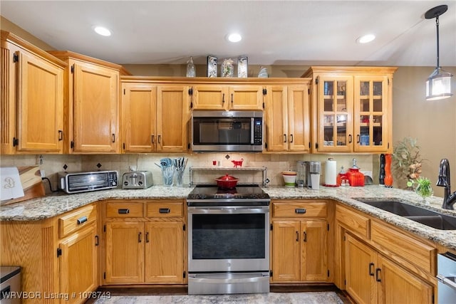 kitchen featuring sink, hanging light fixtures, stainless steel appliances, light stone countertops, and backsplash