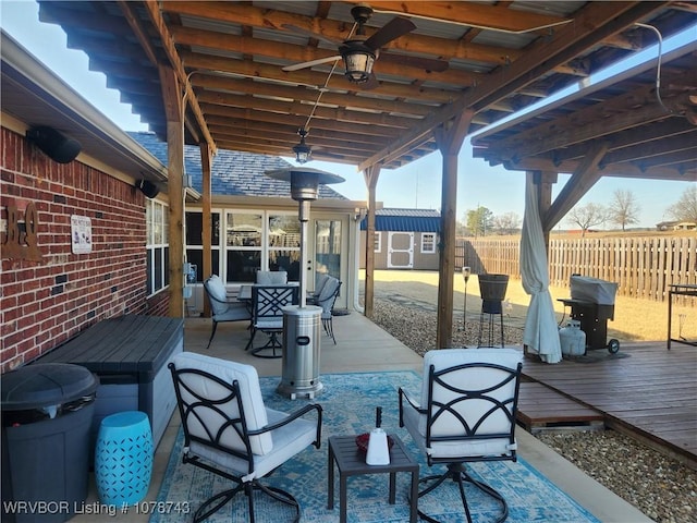 view of patio featuring a wooden deck, ceiling fan, and a storage unit