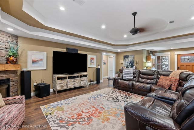 living room with dark hardwood / wood-style flooring, a fireplace, and a raised ceiling