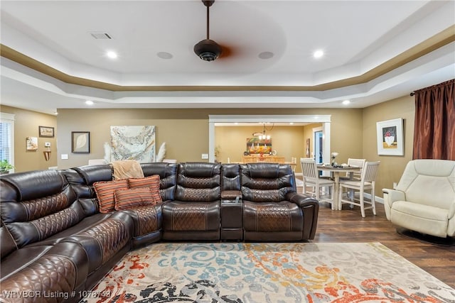 home theater room featuring dark hardwood / wood-style floors and a raised ceiling