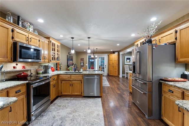 kitchen featuring pendant lighting, sink, kitchen peninsula, stainless steel appliances, and light stone countertops