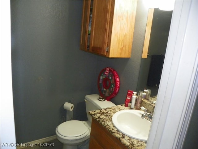 half bathroom with toilet, a textured wall, and vanity