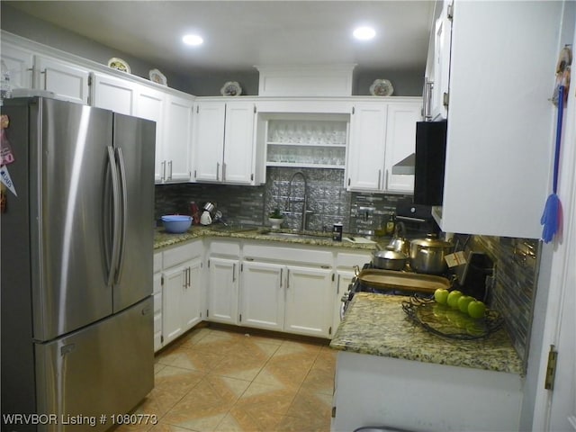 kitchen with freestanding refrigerator, a sink, backsplash, and white cabinets