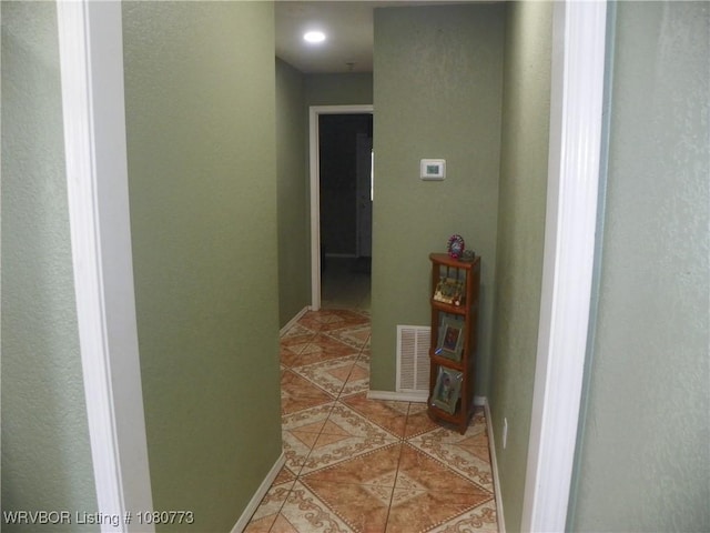 hall with light tile patterned flooring, baseboards, and visible vents