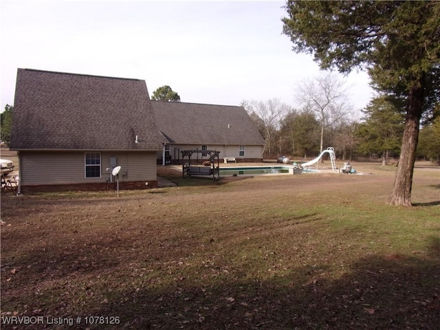 back house at dusk featuring covered porch and a lawn