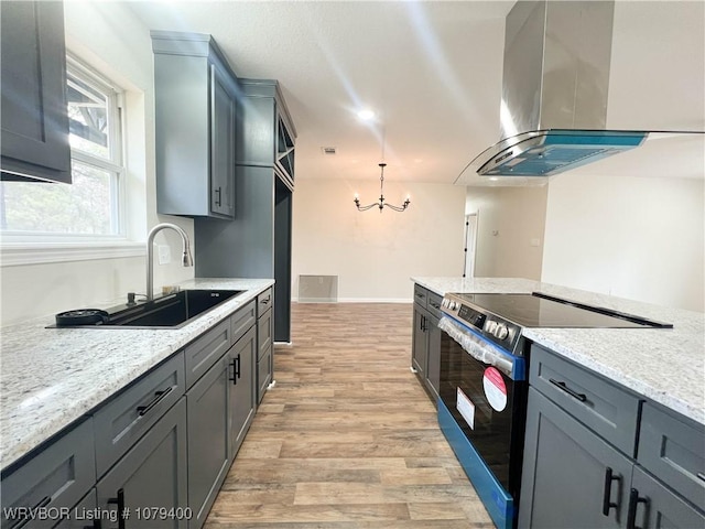 kitchen with light wood finished floors, stainless steel electric range, extractor fan, a chandelier, and a sink