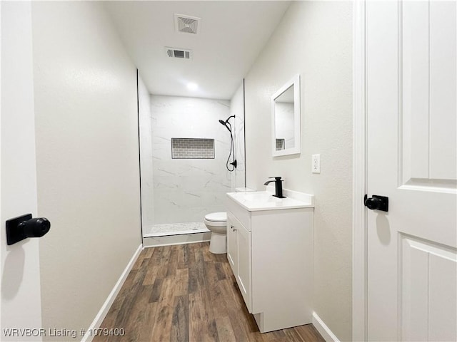 full bathroom featuring a marble finish shower, visible vents, toilet, vanity, and wood finished floors