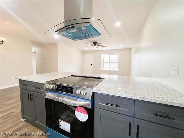 kitchen with light wood-style flooring, gray cabinets, stainless steel range with electric stovetop, and island range hood