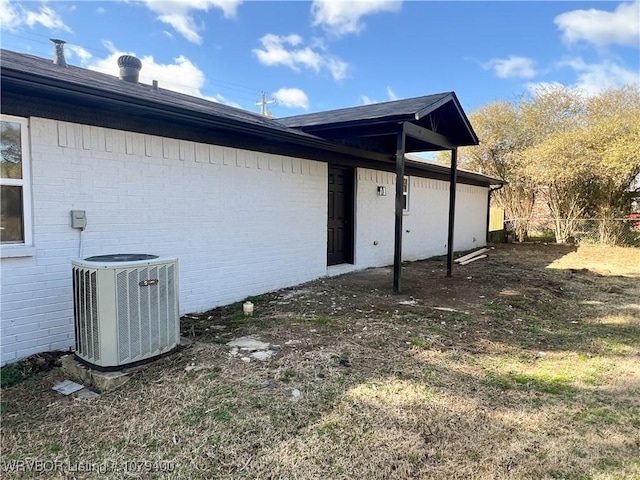 view of side of property with brick siding, fence, and central AC unit