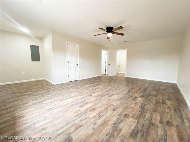 unfurnished room featuring ceiling fan, wood finished floors, electric panel, and baseboards